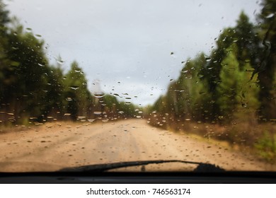 Raindrops on the windshield on the blurred background of a country road