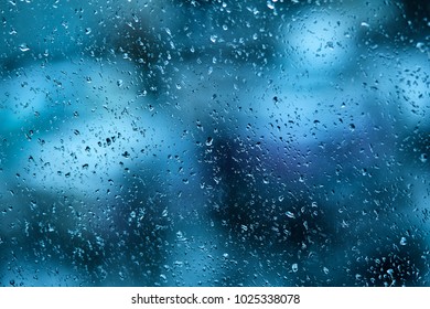 Raindrops on the windshield of the car in the early morning. Transparent glass after rain, cold abstract photo. Texture of glass with scattered rain drops and a blurry background in the late evening. - Shutterstock ID 1025338078