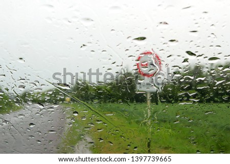 Raindrops on the windshield of a car. View of the road in the rain. Driving in the rain. Concept of travel, rainy or bad weather, meteorology. Selective focus.