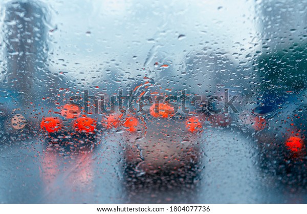 Raindrops on a windshield in rainy\
weather. Heavy rain, poor visibility on a rainy day in the\
city.