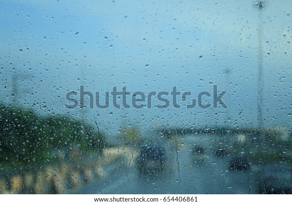 Raindrops on the windshield while driving on a\
rainy day. High way in\
Thailand.