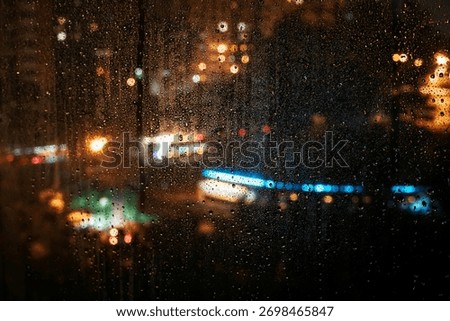 Raindrops slowly trailing down window while blurred city lights shine in distance through the night. Concept of loneliness, emotional silence, unseen presence in rainy solitude