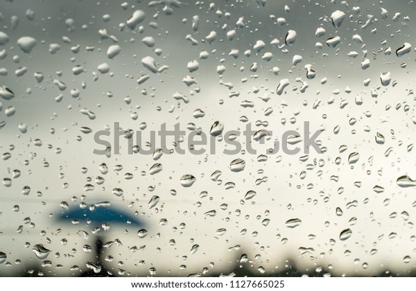 Raindrops splatter on the glass of\
window. View through car window blurry with heavy\
rain.