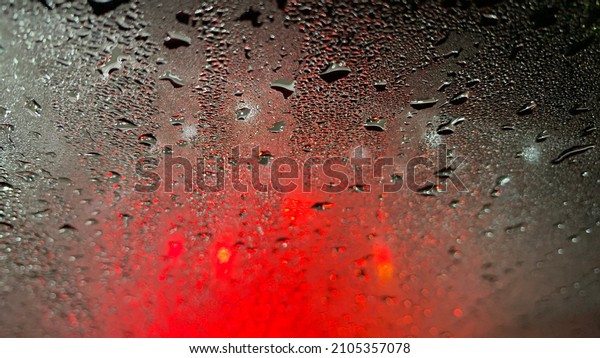 Raindrops at\
the windshield with red dark\
background