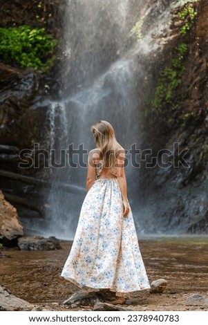 Rainforest waterfall, woman in dress. Waterfalls allure, lady graceful attire. Experience the wild, pristine cascade. Adventure in tropical paradise, unforgettable journey.