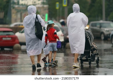 Raining Day In City Center At Summer. Wet People. Raincoats As Protection. Texture Of Strong, Fresh And Powerful Water Drops And Sprays. Tropical Storm. Backs, Rear View