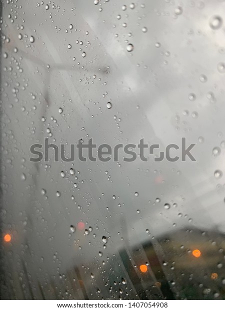 The raining on the car window\
during evening time. There are some lights from the\
houses.
