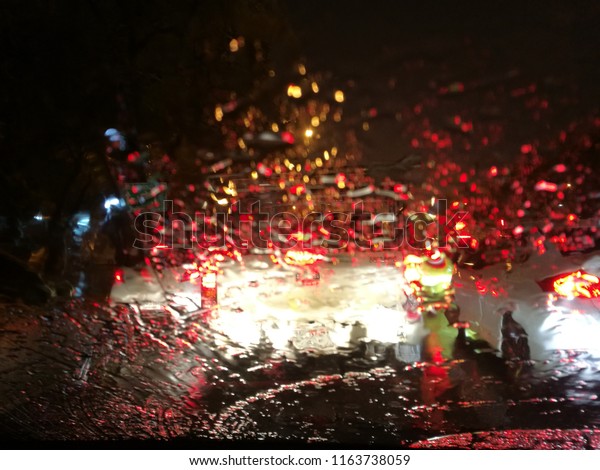Raining on the road blurred vision with night\
time traffic jams in Bangkok\
Thailand