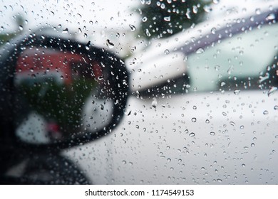 Raining outside the car while driving , rainyday , raindrops on the car glass blur Rain on the car window with out side door mirror with traffic jam