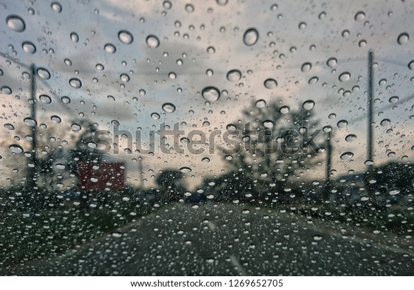 raining outside the car while driving ,
rainyday , raindrops on the car glass blur
view