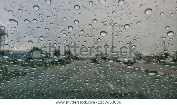 raining outside the car while driving ,\
rainyday , raindrops on the car glass blur\
view