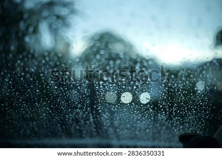 raining outside the car while driving,raindrops on the car glass, water drop front car on rainyday.