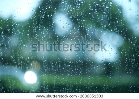raining outside the car while driving,raindrops on the car glass, water drop front car on rainyday.