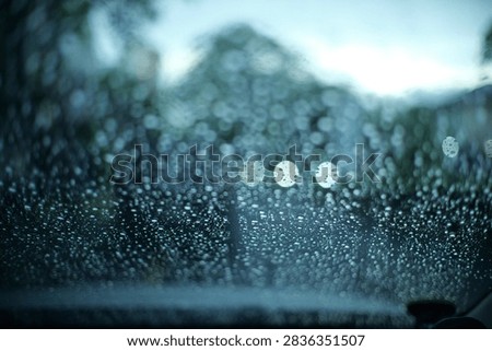 raining outside the car while driving,raindrops on the car glass, water drop front car on rainyday.