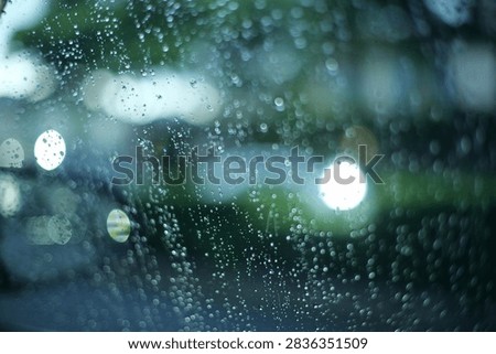 raining outside the car while driving,raindrops on the car glass, water drop front car on rainyday.