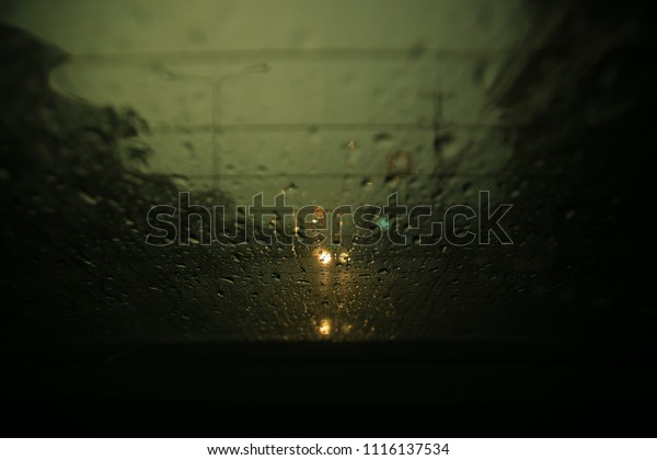 raining in the street. dark cloud and
heavy rain. windshield of a car soak with water droplet. selective
focus on small droplet blur car light in the
background.