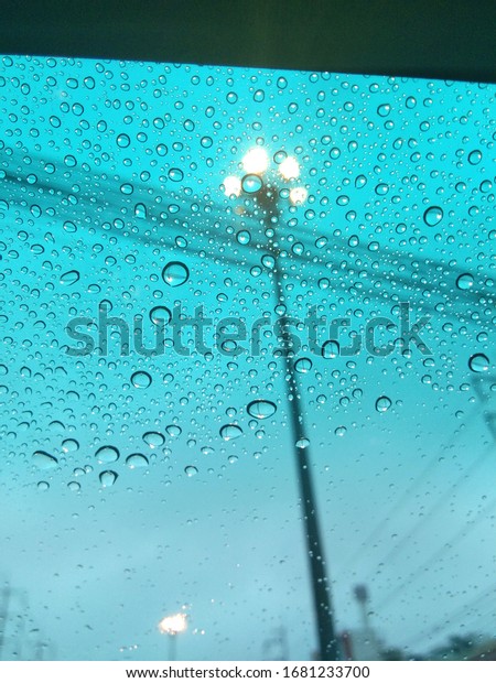 Raining, water droplets dripping on the\
windshield (focused on rain drops on glass), Water droplets on car\
windshield on a rainy in the\
morning.
