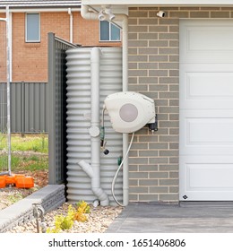 Rainwater Tank And Retractable Hose On The Side Of A House