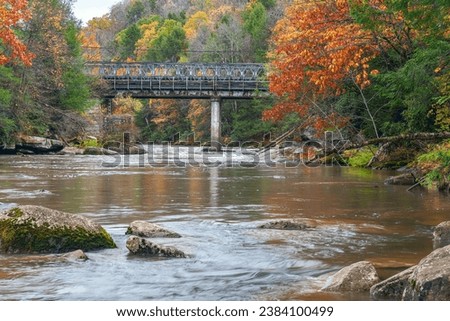 Rainy autumn landscape with a river, fall foliage trees and a railway bridge. Swallow Falls State Park. Oakland. Maryland. USA