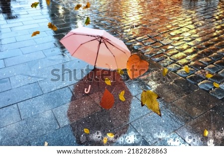 Rainy city street people silhouette with umbrellas Rainy weather season Autumn leaves on window rain drops ,night  blurred light colorful reflection cold season in Tallinn old town  background 