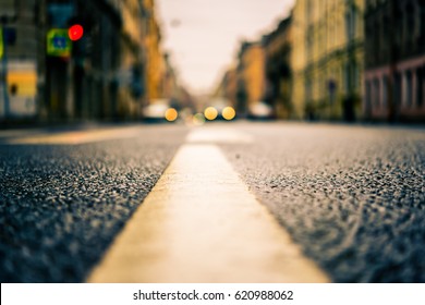 Rainy day in the big city, the headlights of the approaching car. Close up view from the level of the dividing line, image in the orange-blue toning - Shutterstock ID 620988062
