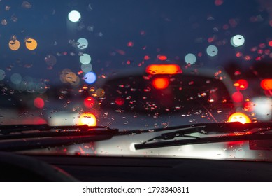 Rainy day in the car view on car traffic jam on rainy day at night traffic lights bokeh with raindrops on carglass  - Powered by Shutterstock