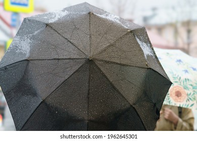 Rainy Day In Moscow. People Are Hiding Under Umbrellas. Lifestyle Concept. The Surface Of The Black Umbrella Covered By Rain Drops And Snow