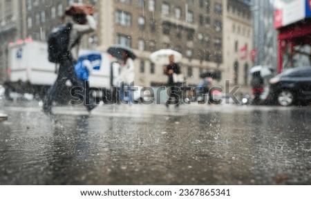 Rainy day in New York city. Wide angle photo during a powerful rain in Manhattan with people with umbrellas crossing the street. Summer storm in America.
