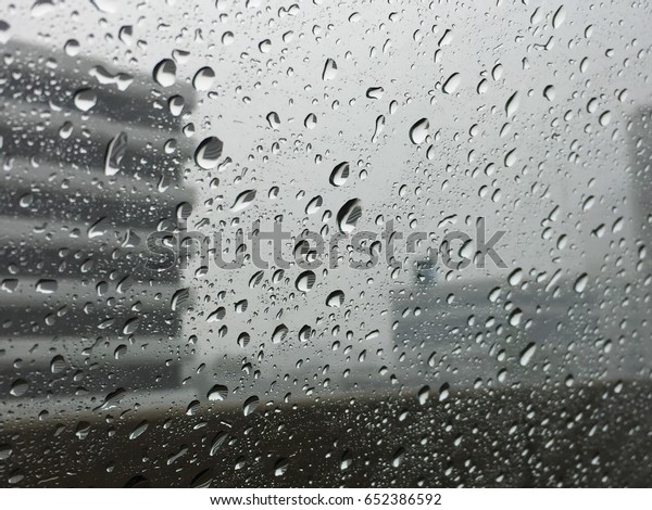 Rainy day , water drops on car glass, car on the\
highway see blurred\
building