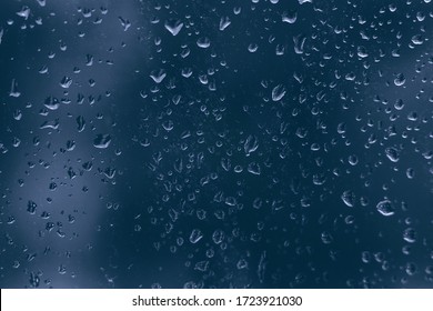 rainy droplets on a dark blue glass window car surface. water drops on transparent background shield in a rainy days in night city . stormy weather. isolation sad depression concept. rainy season.