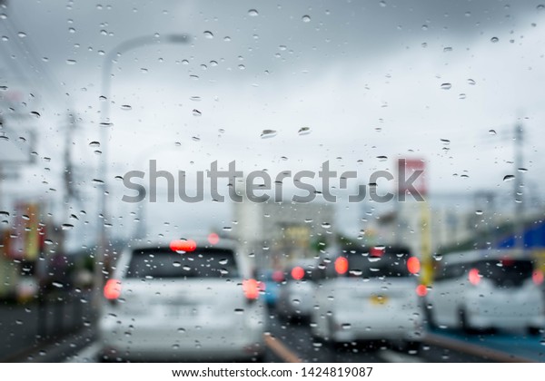 Rainy and gloomy day on\
the road with cars and traffic and rain is focused on the car\'s\
windshield. 