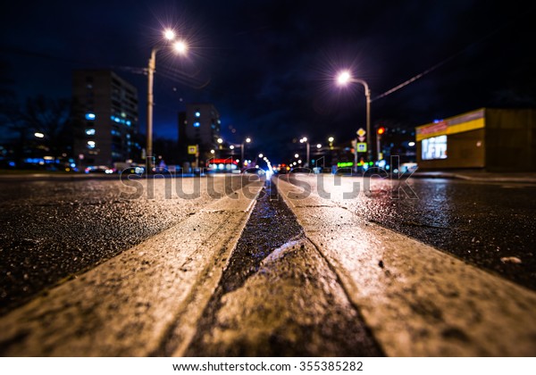 Rainy\
night in the big city, busy crossroad. View from a wide angle at\
the level of the double solid line, in blue\
tones