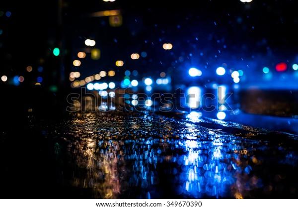 Rainy night in the big\
city, the cars rides on the road. The view from the sidewalk level,\
in blue tones