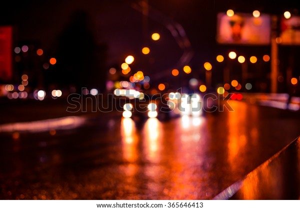 Rainy night in the big city, cars traveling on wet\
highway. View of the highway with a dividing border, image in the\
soft orange-purple toning