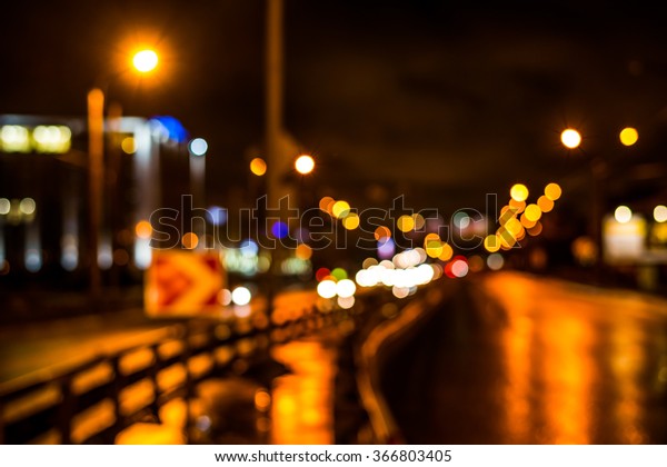 Rainy night in the big city, cars driving on\
highway. Defocused image