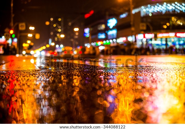 Rainy night in the big city,\
crossroad in the light of shop windows. View from the level of\
asphalt