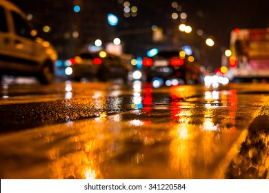 Rainy night in the big city, dense traffic at a busy intersection. View from the level of asphalt