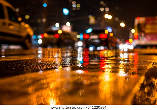 Rainy night in the big city,\
dense traffic at a busy intersection. View from the level of\
asphalt