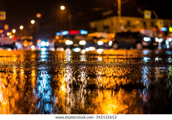 Rainy night in the big city, dense traffic at a\
busy intersection, headlights of passing cars. View from the level\
of asphalt