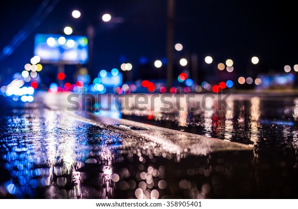 Rainy night in the big city, the\
light from the headlamps of vehicles approaching on the highway.\
View from the level of the dividing line, in blue\
tones