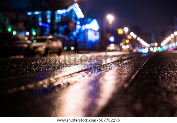 Rainy night in the big city, parked the car on the\
road. Close up view from the level of the double solid line, image\
in the blue tones