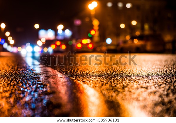 Rainy night in the\
big city, the passing cars on the road. Close up view from the\
level of the dividing\
line