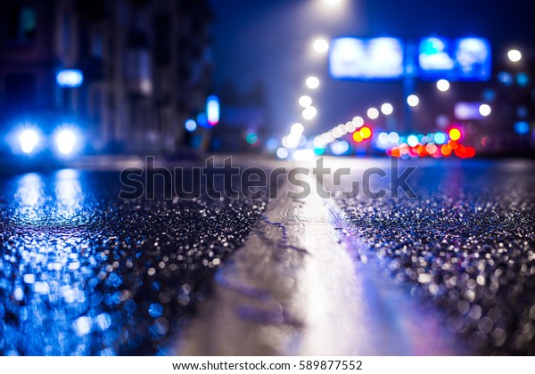 大都会の雨の夜 近づいてくる車の灯りとヘッドライトが灯る街 分割線のレベルからの接写 青のトーンの画像 の写真素材 今すぐ編集