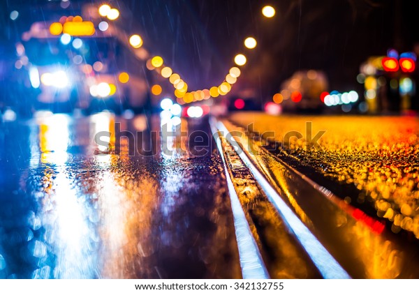 Rainy night in the big\
city, stream of cars traveling along the avenue. View from the tram\
rail level