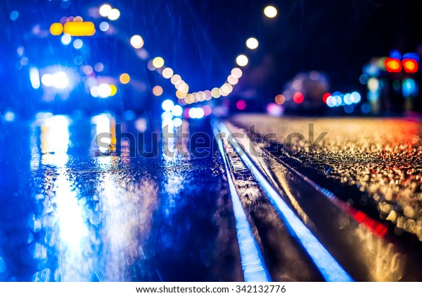 Rainy night\
in the big city, stream of cars traveling along the avenue. View\
from the tram rail level, in blue\
tones