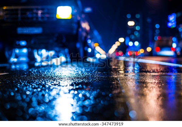 Rainy night\
in the big city, stream of cars traveling along the avenue. View\
from the level of asphalt, in blue\
tones