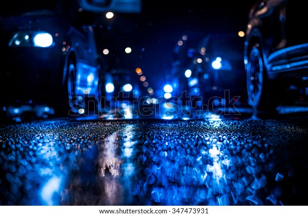 Rainy night
in the big city, stream of cars traveling along the avenue. View
from the level of asphalt, in blue
tones