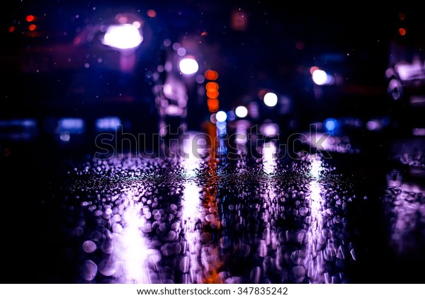Rainy night in the big city, stream of cars\
traveling along the avenue. View from the level of asphalt, image\
in the blue toning