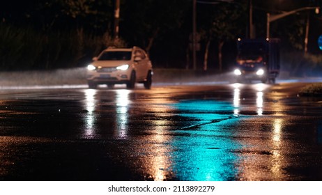 Rainy night in city, cars driving on wet road, rain was illuminated by the headlights of cars, focused on the asphalt road. - Powered by Shutterstock