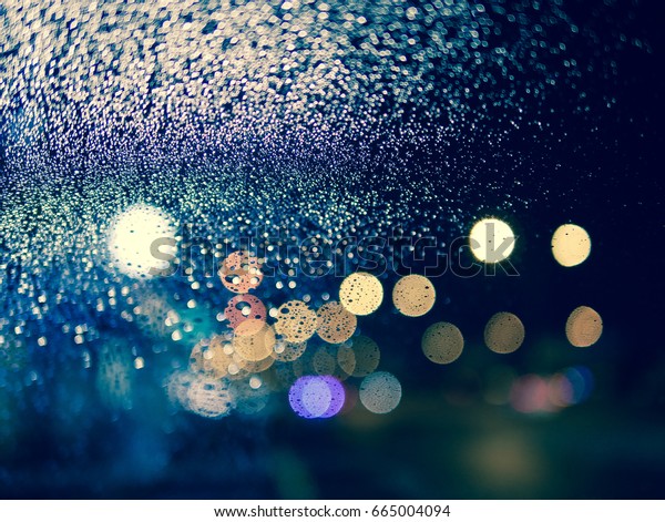 rainy night and street light behind glass window\
with some drops
